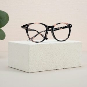 Elegant eyeglasses resting on a white textured block with minimalist design elements.